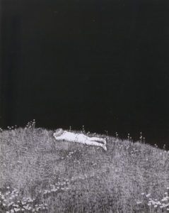 A boy crying laying face down on a field of grass under the night sky